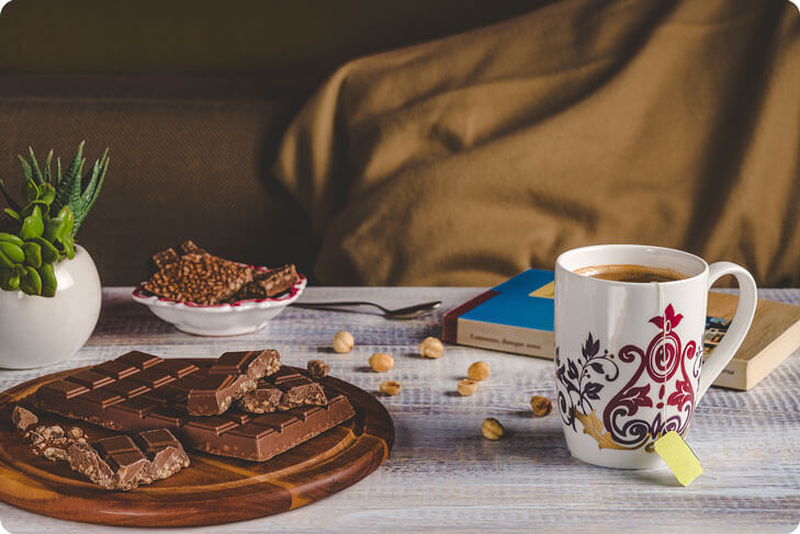 Tavoletta di cioccolato su un tavolo con tisana e libro