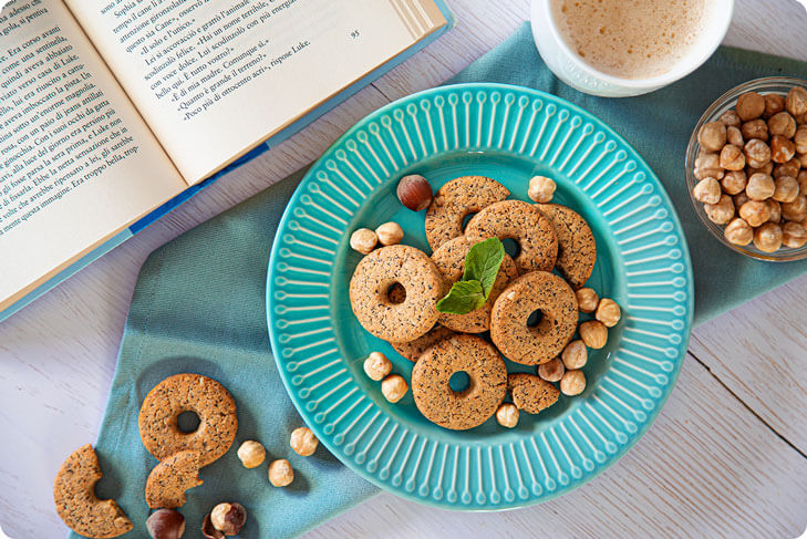 Biscotti proteici alle nocciole a colazione con un libro e un cappuccino
